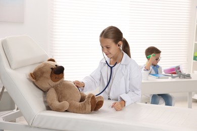 Photo of Little boy and girl with toy pretending to be doctors indoors