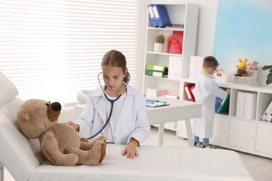 Little boy and girl with toy pretending to be doctors indoors