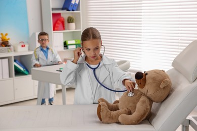 Photo of Little boy and girl with toy pretending to be doctors indoors