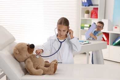 Photo of Little boy and girl with toy pretending to be doctors indoors