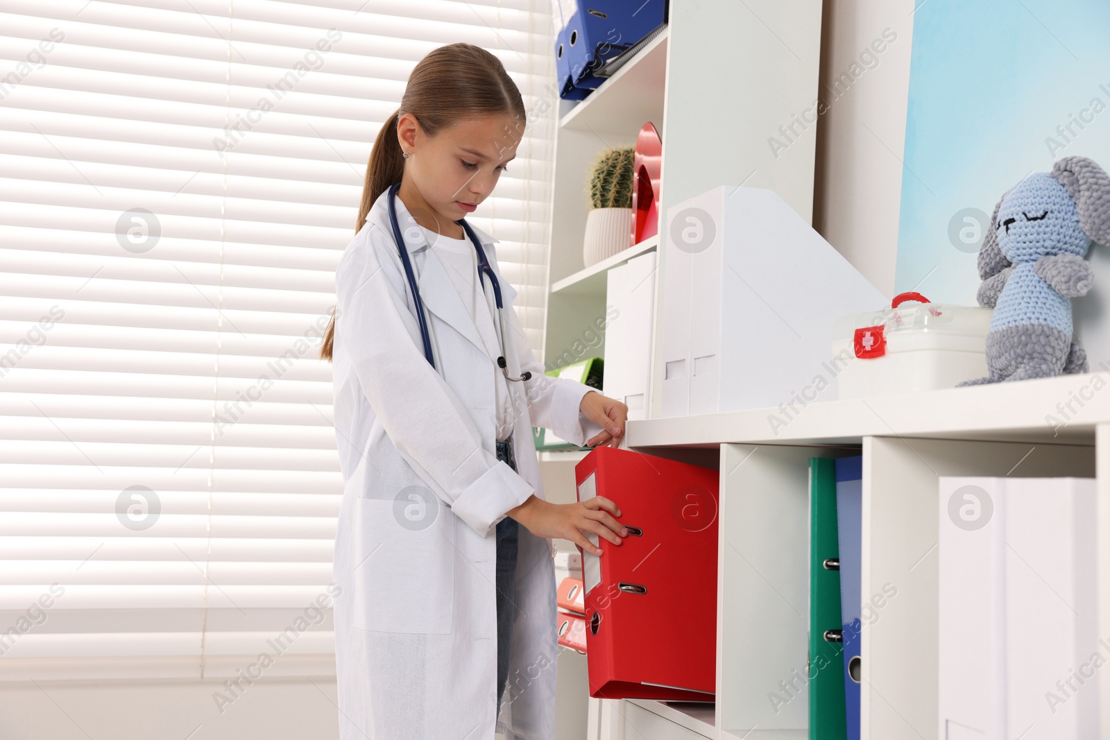 Photo of Girl with stethoscope pretending to be doctor indoors