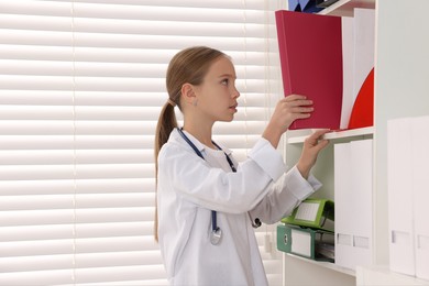 Photo of Girl with stethoscope pretending to be doctor indoors