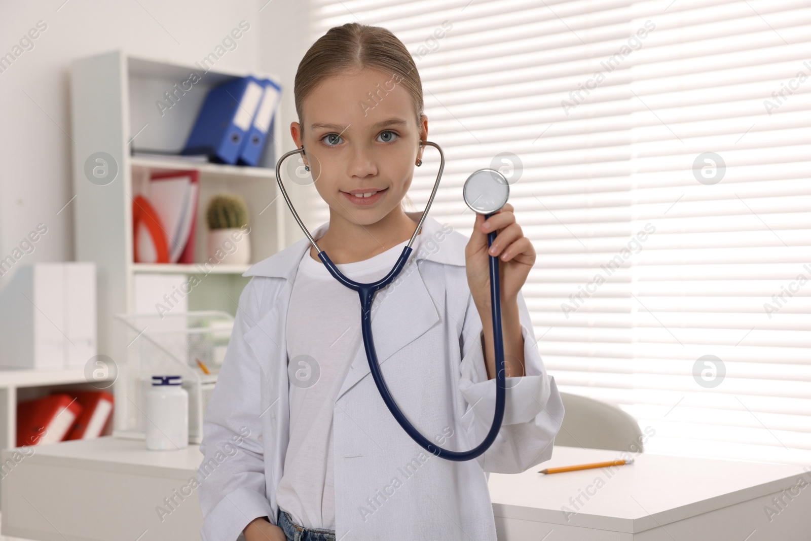 Photo of Girl with stethoscope pretending to be doctor indoors