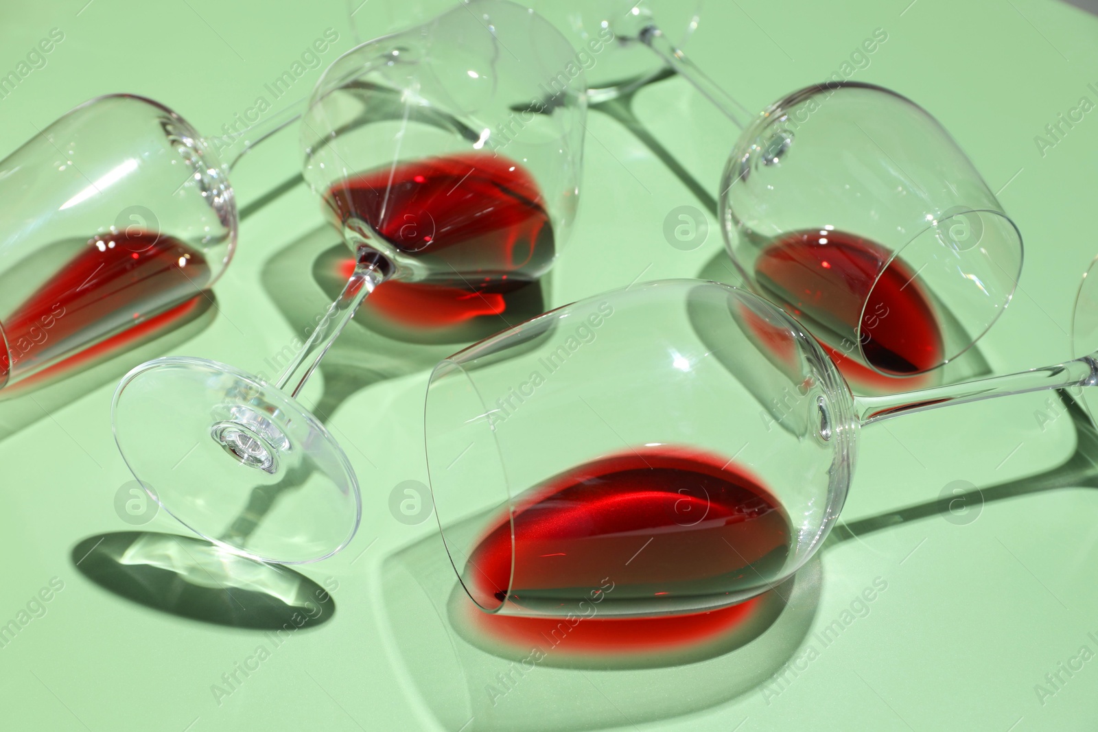 Photo of Glasses of red wine on light green background, closeup