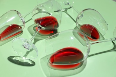 Photo of Glasses of red wine on light green background, closeup