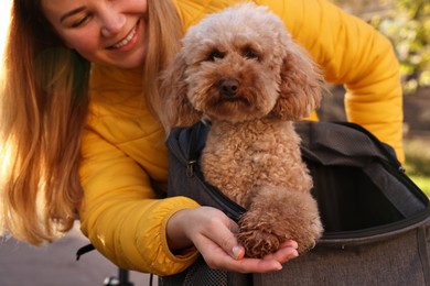 Photo of Woman with cute Toy Poodle dog outdoors