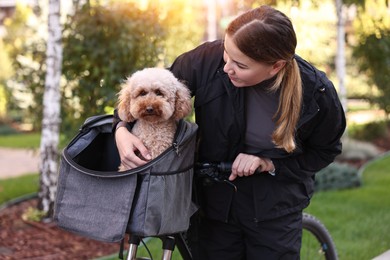 Photo of Woman with bicycle and cute Toy Poodle dog in pet carrier outdoors