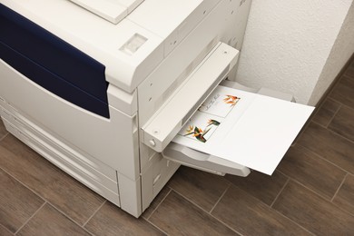 Photo of Modern printer with paper indoors. Printing house