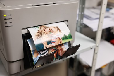 Modern printer with colorful photos indoors, closeup