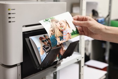 Photo of Woman with colorful photos near modern printer indoors, closeup