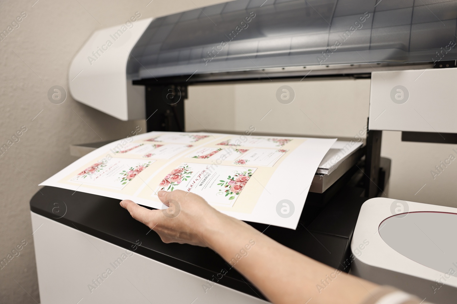 Photo of Woman using modern printer indoors, closeup. Printing house