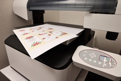 Photo of Modern printer with printed wedding invitation cards indoors, closeup. Printing house