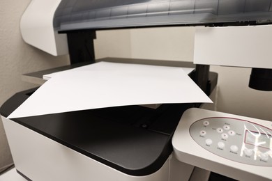 Photo of Modern printer with paper indoors, closeup. Printing house