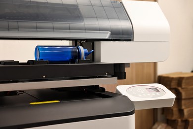 Photo of Modern printer and empty bottle indoors, closeup