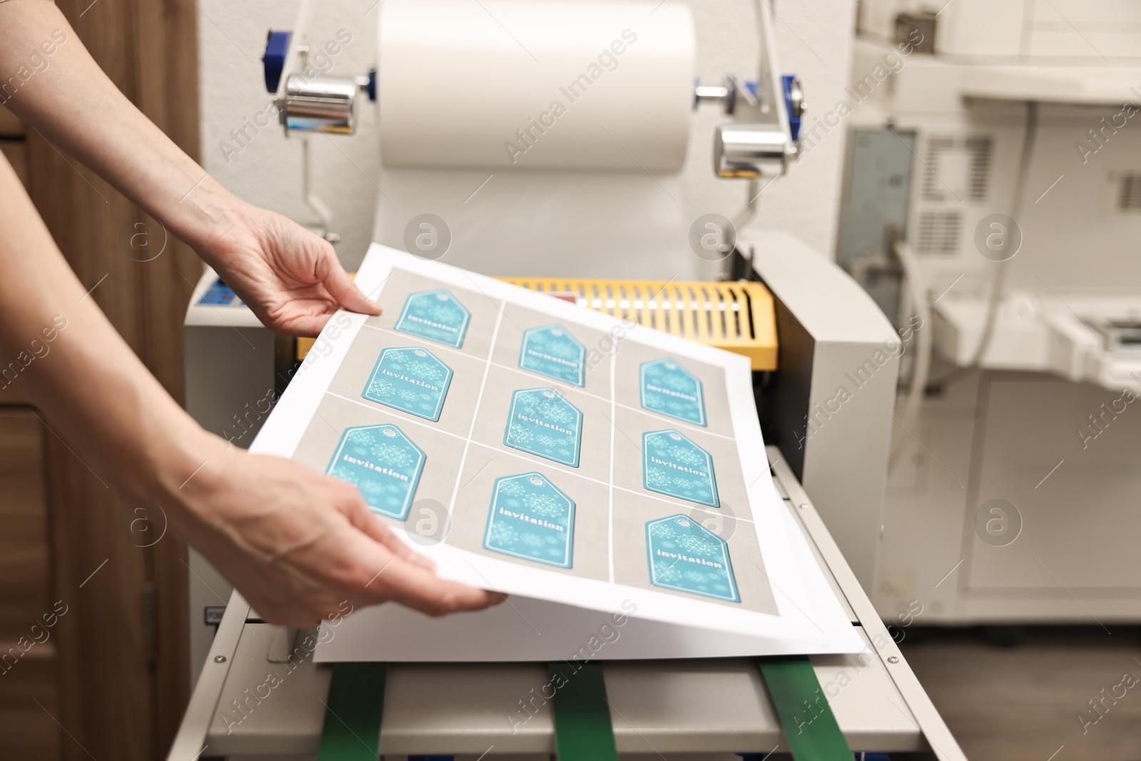 Photo of Woman with printed invitation tags indoors, closeup. Printing house