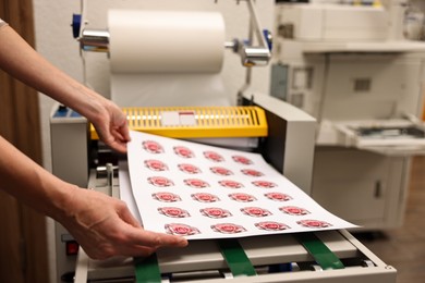 Photo of Woman with printed flower stickers indoors, closeup. Printing house