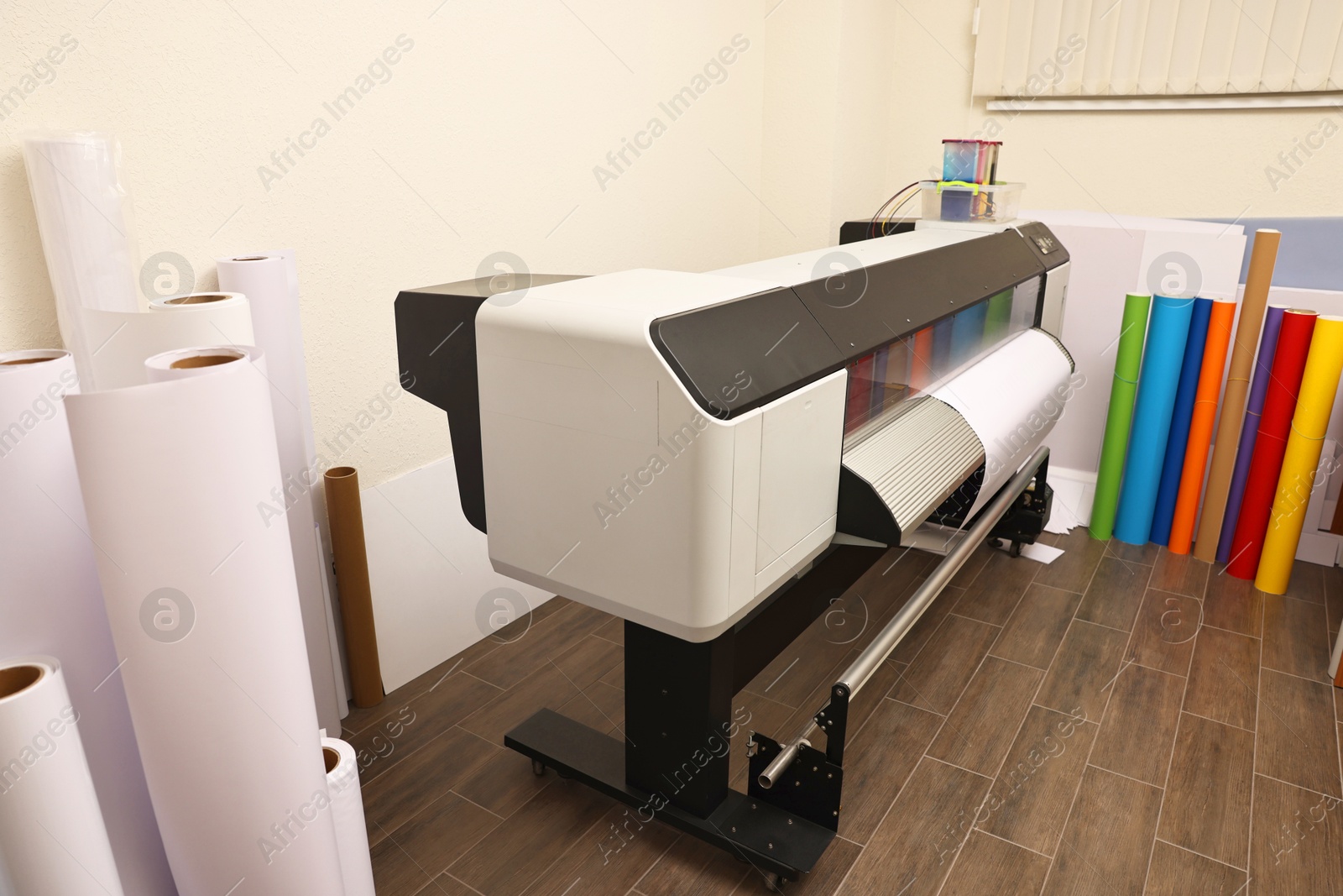 Photo of Wide-format printer and paper rolls indoors. Printing house