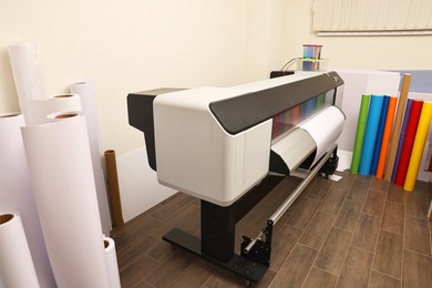 Photo of Wide-format printer and paper rolls indoors. Printing house