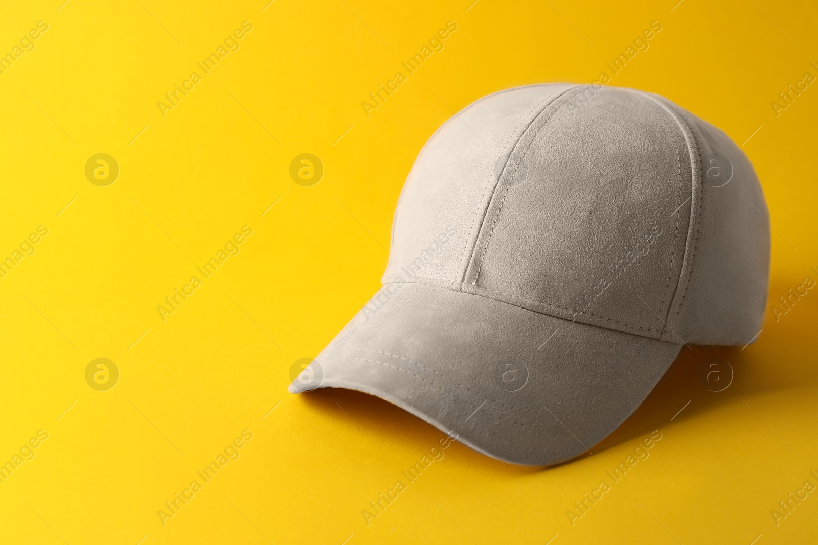 Photo of Stylish baseball cap on yellow background. Mockup for design