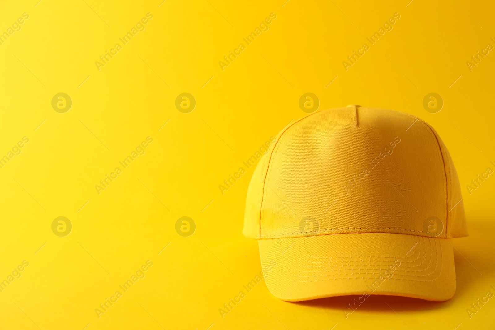 Photo of Stylish baseball cap on yellow background. Mockup for design