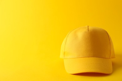 Photo of Stylish baseball cap on yellow background. Mockup for design