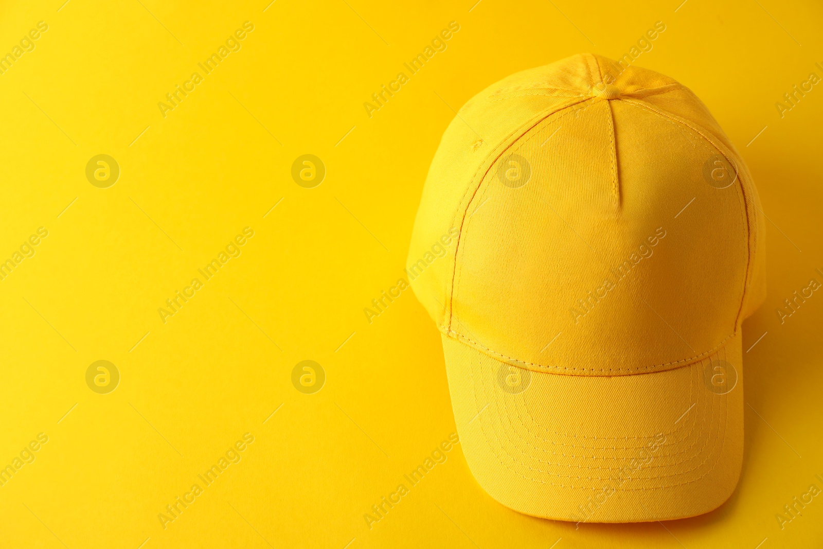 Photo of Stylish baseball cap on yellow background. Mockup for design