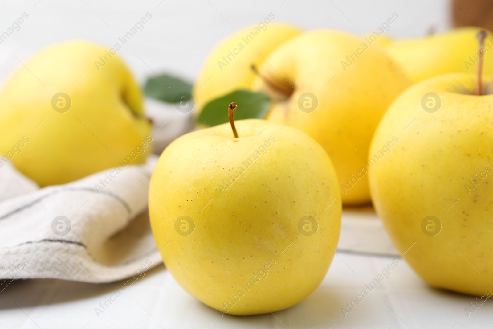 Photo of Fresh ripe yellow apples on white tiled table, closeup