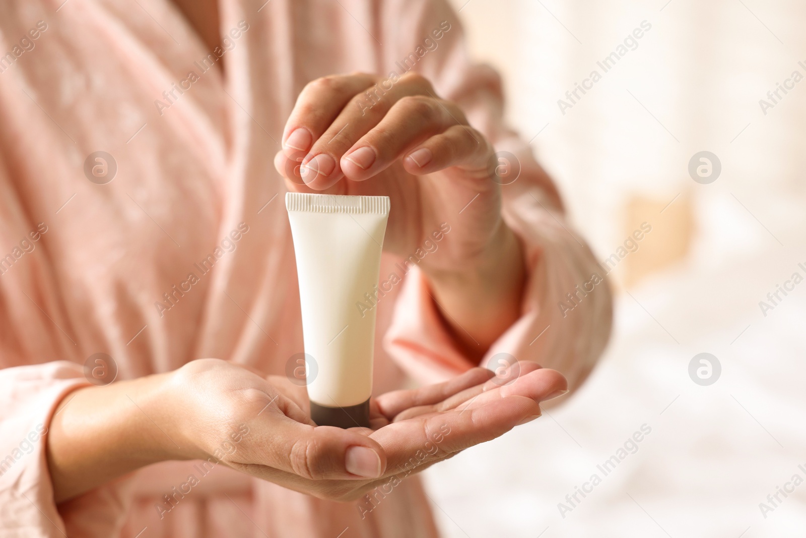 Photo of Woman with tube of cream at home, closeup