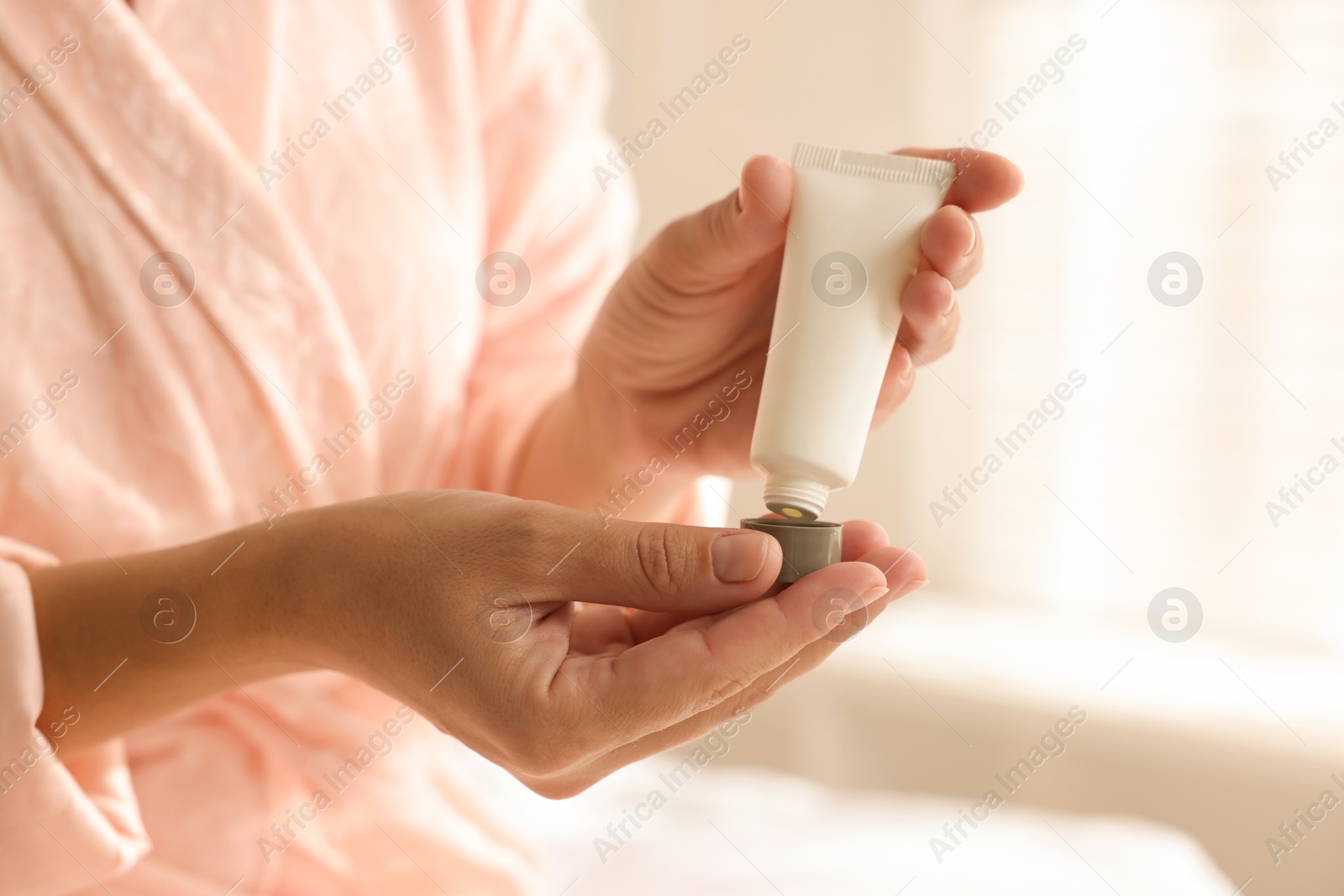 Photo of Woman with tube of cream at home, closeup