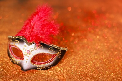 Photo of Beautiful carnival mask on shiny color background, closeup. Space for text