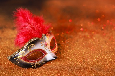 Photo of Beautiful carnival mask on shiny color background, closeup. Space for text