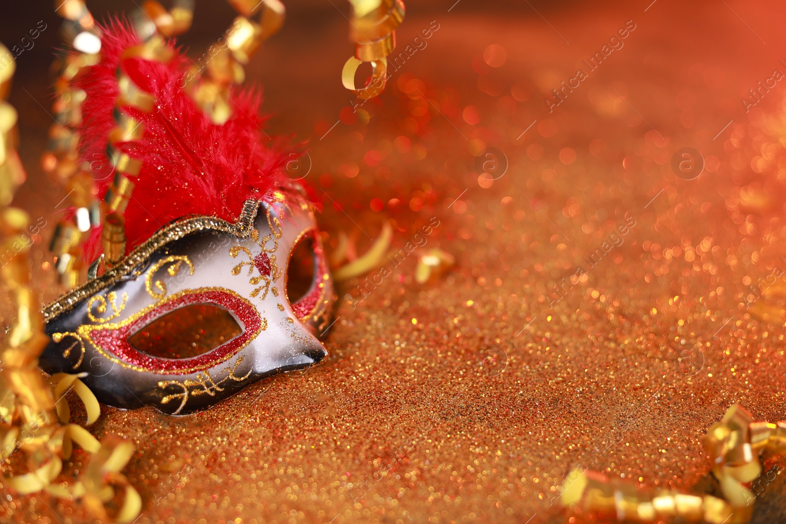 Photo of Beautiful carnival mask on shiny color background, closeup. Space for text