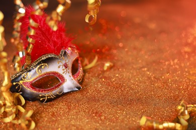 Photo of Beautiful carnival mask on shiny color background, closeup. Space for text