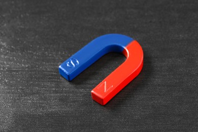 Photo of One horseshoe magnet on black wooden table, closeup