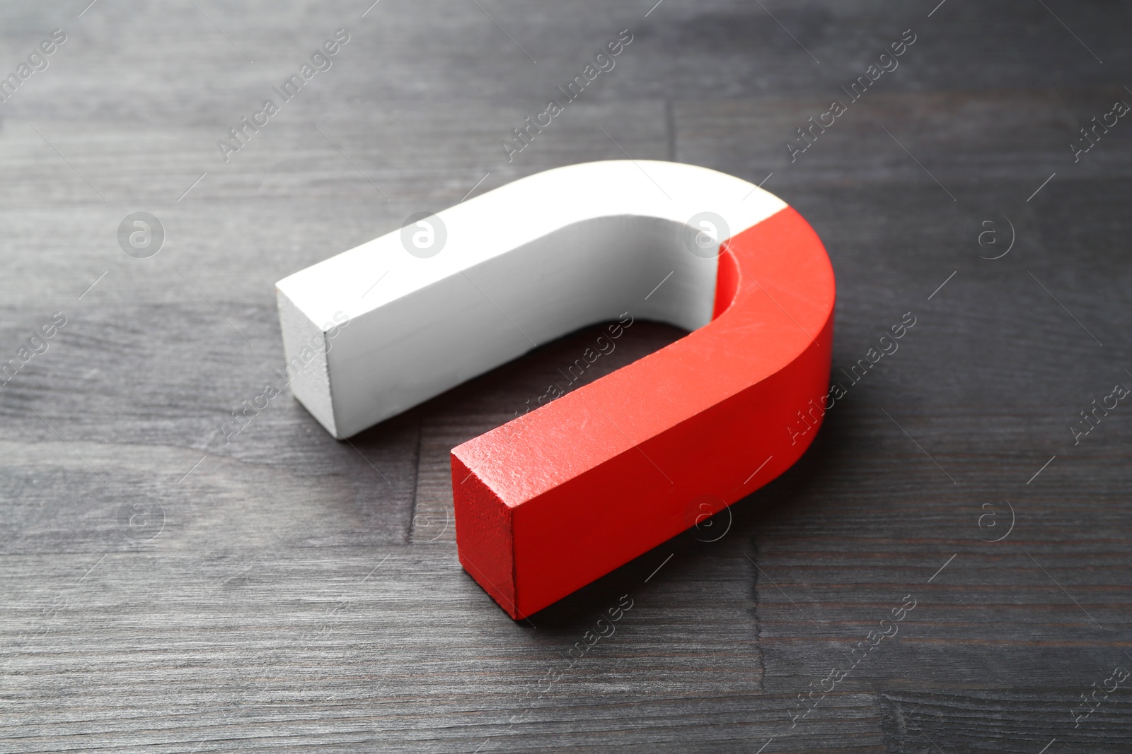 Photo of One horseshoe magnet on black wooden table, closeup