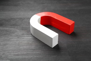 Photo of One horseshoe magnet on black wooden table, closeup