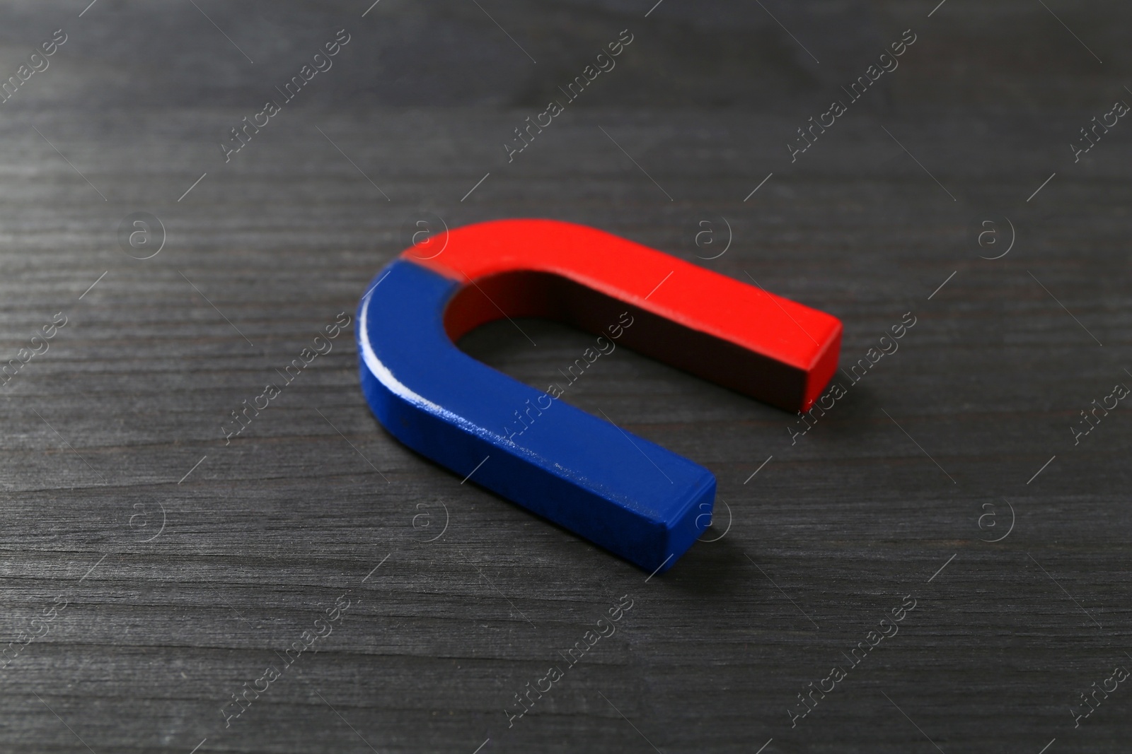 Photo of One horseshoe magnet on black wooden table, closeup