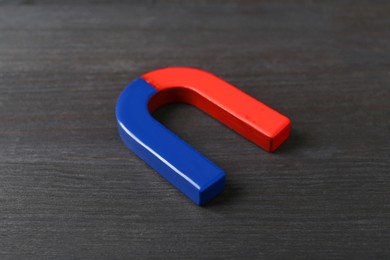 Photo of One horseshoe magnet on black wooden table, closeup