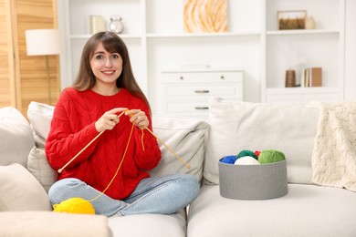 Photo of Beautiful woman knitting on sofa at home