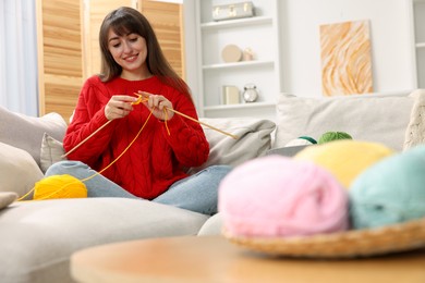 Photo of Beautiful woman knitting on sofa at home