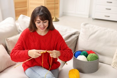 Photo of Beautiful woman knitting on sofa at home