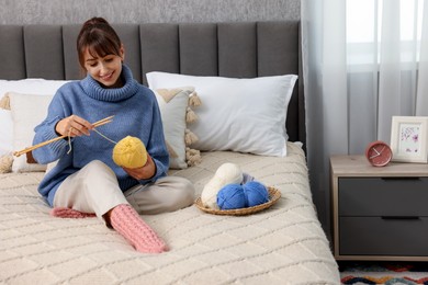 Photo of Beautiful woman knitting with needles on bed at home