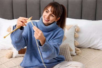 Photo of Beautiful woman knitting with needles on bed at home