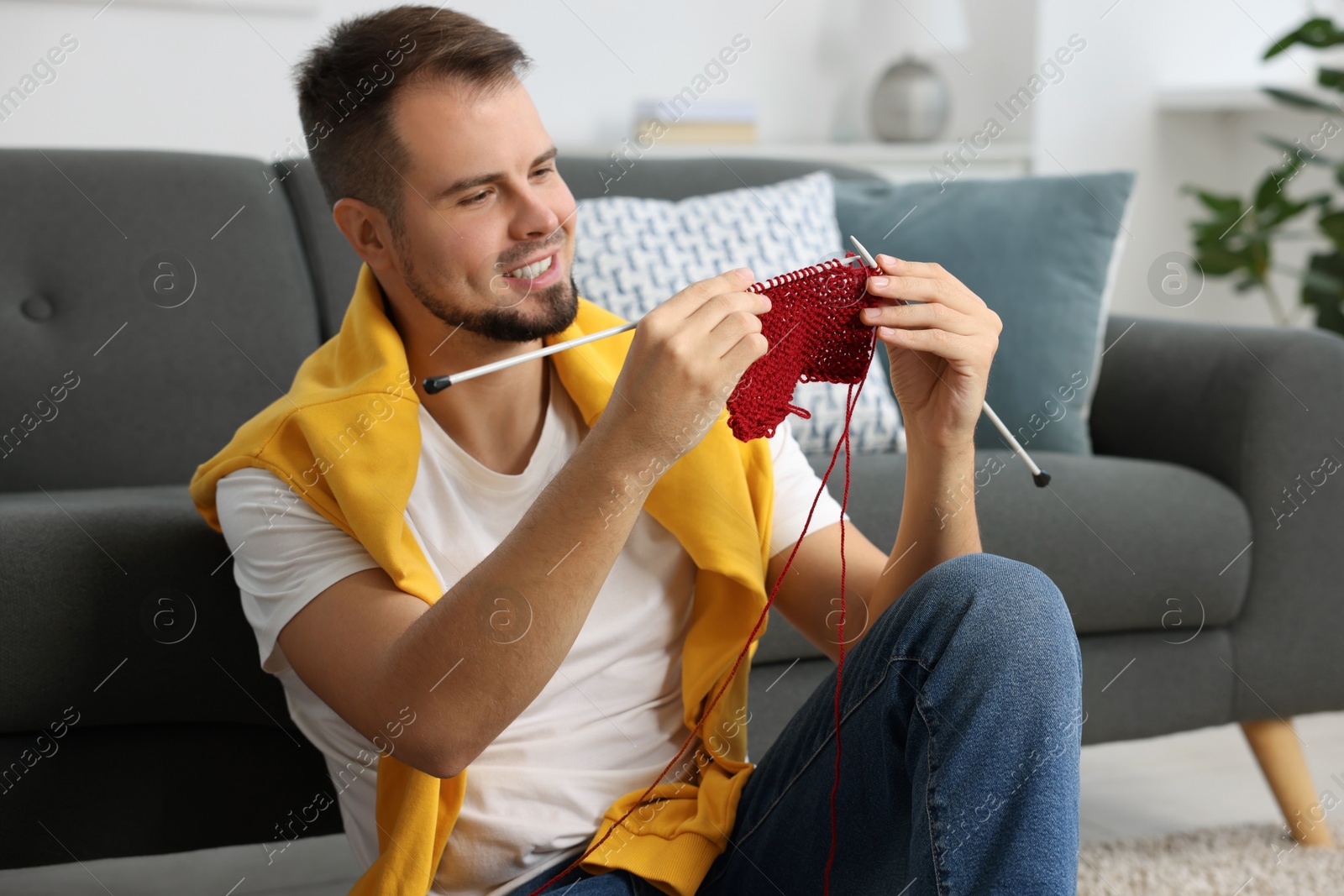 Photo of Man knitting with needles on floor at home