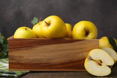 Photo of Ripe yellow apples in wooden crate on table