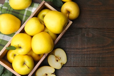 Photo of Ripe yellow apples in crate on wooden table, top view. Space for text