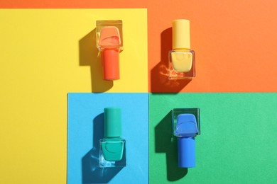 Photo of Nail polishes in bottles on color background, flat lay