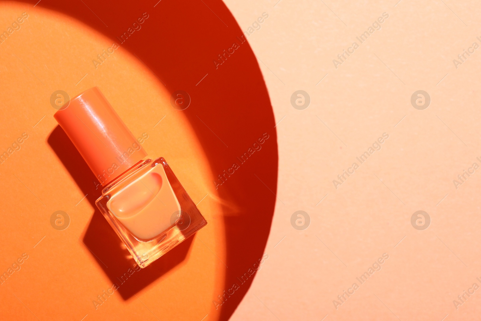 Photo of Nail polish in bottle on color background, top view. Space for text