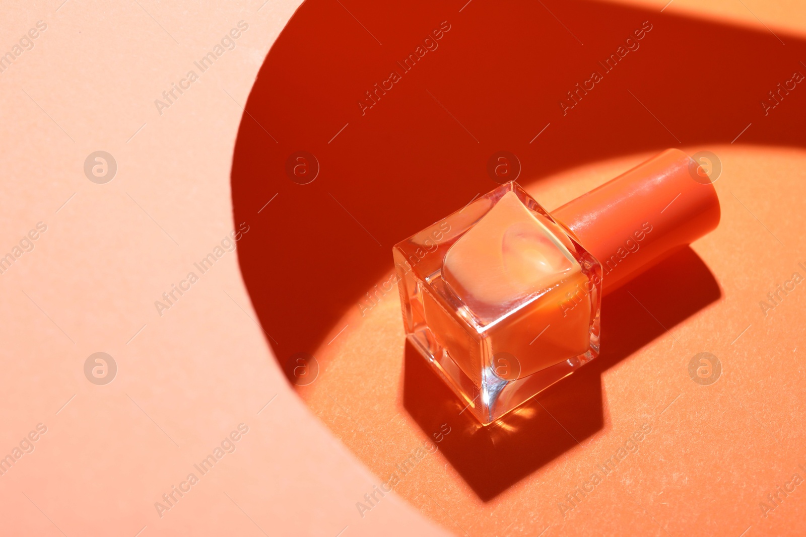 Photo of Nail polish in bottle on color background, space for text