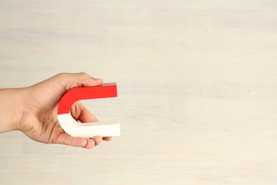 Photo of Man holding horseshoe magnet against white wooden background, closeup. Space for text